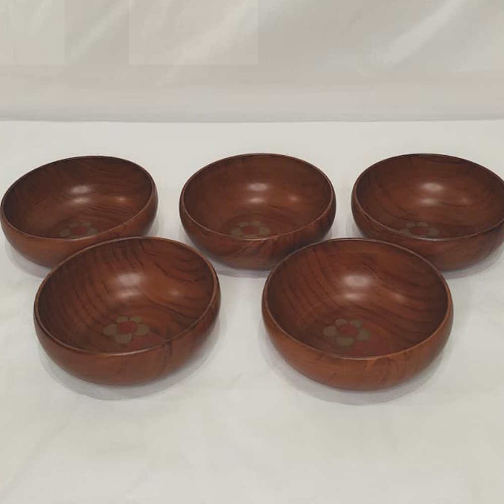 Ensemble de quatre bols artisanaux en bois brun avec motifs floraux discrets.