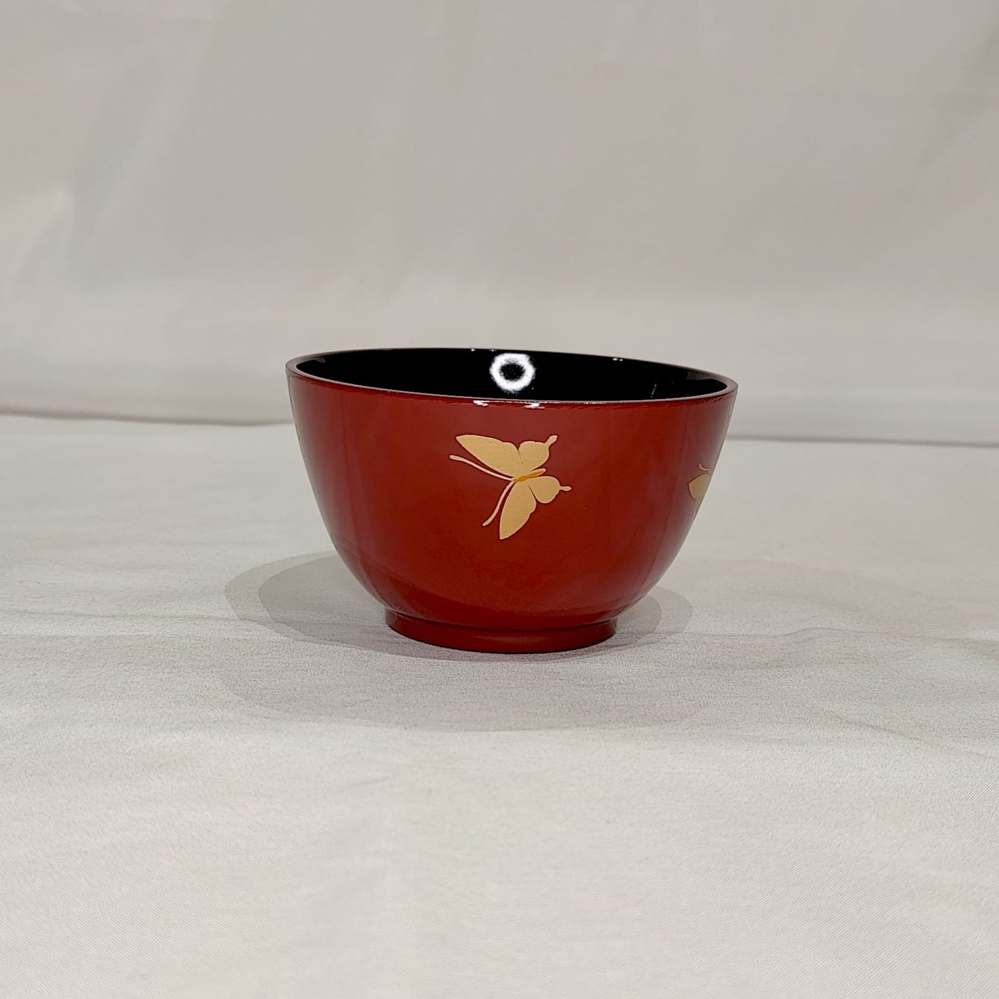 Bol japonais rouge laqué avec motif papillon doré sur fond blanc